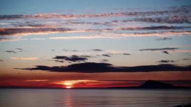 Sabahın erken saatlerinde denizde hareket eden bulutların hızlanması, güneşin doğması. Gandia Sahili, Valencia İspanya manzarası. Montgo dağının silueti ufukta belirdi.