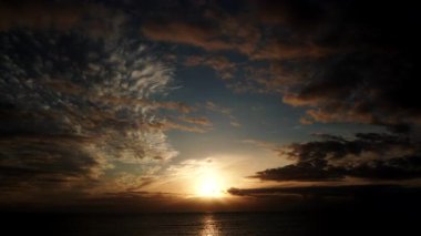 Sabahın ilk ışıklarıyla deniz manzarası. Bulutların zaman akışı denizde hareket ediyor ve güneş doğuyor. İspanya 'daki doğa manzarası.