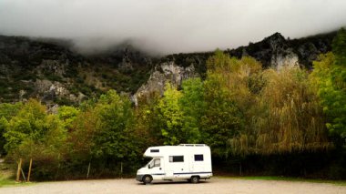 Yağmurlu bir günde, kayalık dağlarda kamp yapan karavan. Agurain, Bask bölgesi, İspanya. Karavanla macera.