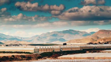 İspanya kıyılarında büyük ticari cam seralar ile hareket eden bulutların zaman akışı. Endüstriyel tarım. Murcia bölgesi, İspanya.