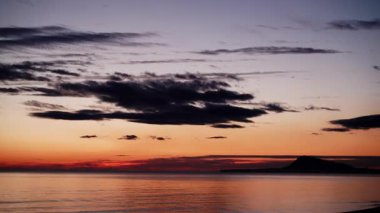 Sabahın erken saatlerinde denizde hareket eden bulutların hızlanması, güneşin doğması. Doğa manzarası. Gandia Sahili, Valencia İspanya.
