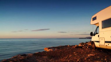Kamp aracı deniz kenarında kamp yapıyor. Karavanla seyahat ediyorum. Karavan tatili. Doğa ve aktiviteler. Zaman Uygulaması