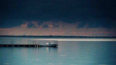 Akşamları tahta iskeleye bağlı bir tekne ile deniz manzarası. Baltık Denizi, Polonya 'da Puck Körfezi ve ufukta Hel Yarımadası. Deniz kıyısı manzarası.