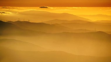 Rüzgar türbinleri gün batımında bulutların üzerinde. Portekiz 'deki Torre Dağı tepesinden Serra da Estrela' nın görüntüsü.