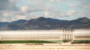 İspanya kıyılarında büyük ticari cam seralar ile hareket eden bulutların zaman akışı. Endüstriyel tarım. Murcia bölgesi, İspanya.