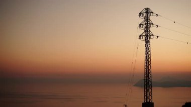 Gün batımında kıyı şeridi, elektrik iletim direkleriyle, elektrik hatları yüksek voltaj kuleleriyle. Ben roldan, Cabo de gata nijar, İspanya.