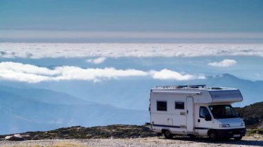 Karavan bulutların üstündeki dağlarda kamp yapıyor. Portekiz, Serra da Estrela 'nın Torre Dağı zirvesi. Ziyaret yeri. Macera ve gezici ev tatili. Zaman Uygulaması