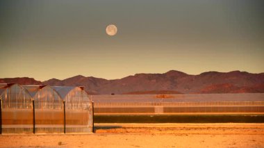 İspanya kıyı manzarası, gökyüzünde ay ve sabah ışığında büyük ticari cam seralar. Endüstriyel tarım. Murcia bölgesi, İspanya.