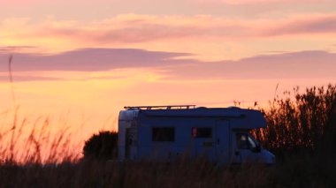 Karavan, gün doğumunda deniz kenarındaki çayır tarlasında kamp yapan eğlence aracı. Capi Corb konumu, Valencia, Akdeniz kıyısındaki İspanya. Karavanla yolculuk..