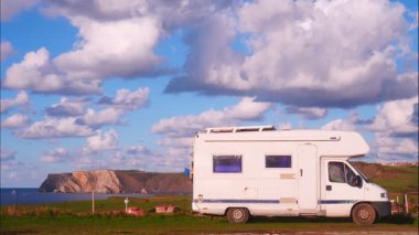 İspanya 'nın kuzeyindeki Asterias sahilindeki Verdicio plajında kamp yapan karavanın üzerinden geçen bulutların hızlanması. Cape Penas uçurumu uzakta. Karavanla git..