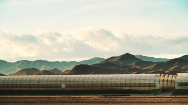 İspanya kıyılarında büyük ticari cam seralar ile hareket eden bulutların zaman akışı. Endüstriyel tarım. Murcia bölgesi, İspanya.