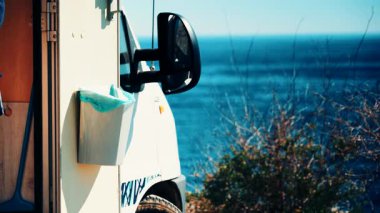 İçinde mavi plastik poşet olan çöp tenekesi karavan kapısında asılı. Deniz kıyısında kamp yapmak. Tatiller ve karavanla seyahat.