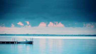 Akşamları su üzerinde hareket eden bulutlar ve iskeleye bağlı tekneler. Baltık Denizi, Puck Bay in poland ve hel yarımadası ufukta. Deniz kıyısı manzarası.