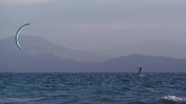 Uçurtma kaykayı. Uçurtma sörfçüsü dalgalarda sörf yapar, tarifa İspanya. Spor aktivitesi. Uçurtma yarışı. Yavaş çekim.