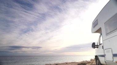 Bulutlar, deniz kenarında kamp yapan karavanın üzerinden geçiyor. Karavanla seyahat ediyorum. Karavan tatili. Doğa ve faaliyetler.