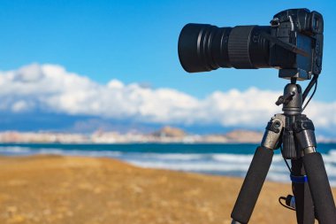 Profesyonel kamera tripodun üzerinde deniz kıyısı manzarasının videosunu çekiyor, İspanya.