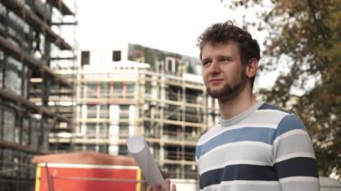 Gayrimenkul ailesi ve konut geliştirme kavramı - yeni büyük modern ev inşaatı alanının önündeki genç adam ev 4K Prores Hq kodlamasını hayal ediyor