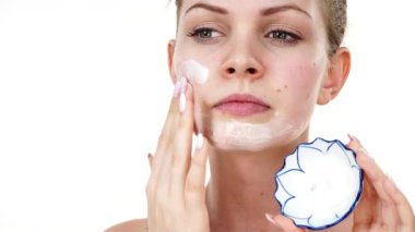 Maske takan genç bir kadın yüzüne nemlendirici krem sürüyor. Cilt nemlendiricisine dikkat eden bir kız. Cilt bakımı.