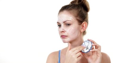 Maske takan genç bir kadın yüzüne nemlendirici krem sürüyor. Cilt nemlendiricisine dikkat eden bir kız. Cilt bakımı.