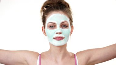 Yüzünde beyaz yeşil çamur maskesi olan genç kadın, turuncu meyve yarısını tutan, gözleri kapsayan. Genç kız cilt bakımı. Güzellik tedavisi.