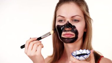 Genç bir kadın yüzüne karbonhidrat temizleme maskesi takıyor, yüzüne, beyaza. Genç kız yağlı cildiyle ilgileniyor, gözenekleri temizliyor. Güzellik tedavisi. Cilt bakımı.