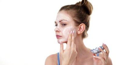 Maske takan genç bir kadın yüzüne nemlendirici krem sürüyor. Cilt nemlendiricisine dikkat eden bir kız. Cilt bakımı.