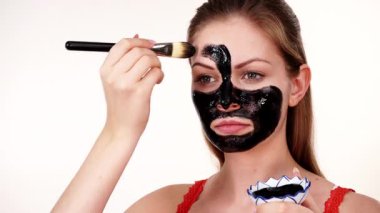 Genç bir kadın yüzüne karbonhidrat temizleme maskesi takıyor, yüzüne, beyaza. Genç kız yağlı cildiyle ilgileniyor, gözenekleri temizliyor. Güzellik tedavisi. Cilt bakımı.