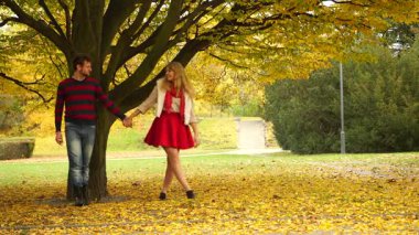 Genç çiftin sonbahar parkında el ele tutuşup öpüşmeleri. Sonbahar aşkı kavramı birliktelik ve ilişki 4k karargah kodlaması gerektirir