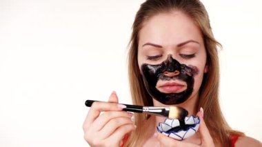 Genç bir kadın yüzüne karbonhidrat temizleme maskesi takıyor, yüzüne, beyaza. Genç kız yağlı cildiyle ilgileniyor, gözenekleri temizliyor. Güzellik tedavisi. Cilt bakımı.