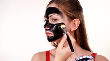 Genç bir kadın yüzüne karbonhidrat temizleme maskesi takıyor, yüzüne, beyaza. Genç kız yağlı cildiyle ilgileniyor, gözenekleri temizliyor. Güzellik tedavisi. Cilt bakımı.