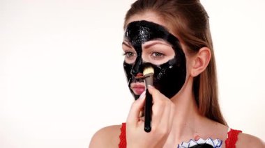 Genç bir kadın yüzüne karbonhidrat temizleme maskesi takıyor, yüzüne, beyaza. Genç kız yağlı cildiyle ilgileniyor, gözenekleri temizliyor. Güzellik tedavisi. Cilt bakımı.