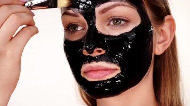 Genç bir kadın yüzüne karbonhidrat temizleme maskesi takıyor, yüzüne, beyaza. Genç kız yağlı cildiyle ilgileniyor, gözenekleri temizliyor. Güzellik tedavisi. Cilt bakımı.