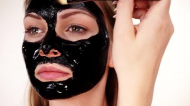 Genç bir kadın yüzüne karbonhidrat temizleme maskesi takıyor, yüzüne, beyaza. Genç kız yağlı cildiyle ilgileniyor, gözenekleri temizliyor. Güzellik tedavisi. Cilt bakımı.