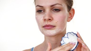 Maske takan genç bir kadın yüzüne nemlendirici krem sürüyor. Cilt nemlendiricisine dikkat eden bir kız. Cilt bakımı.