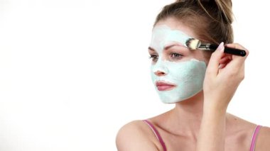 Yüzüne yeşil çamur maskesi dayayan genç bir kadın. Genç kız yağlı cildiyle ilgileniyor, gözenekleri temizliyor. Güzellik tedavisi. Cilt bakımı.