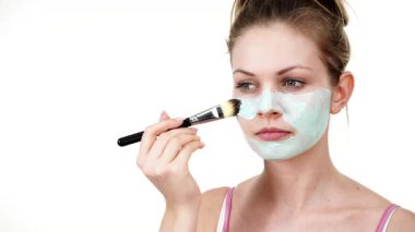 Yüzüne yeşil çamur maskesi dayayan genç bir kadın. Genç kız yağlı cildiyle ilgileniyor, gözenekleri temizliyor. Güzellik tedavisi. Cilt bakımı.