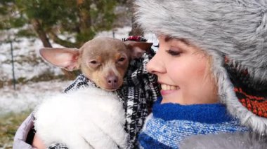 Köpeğiyle oynayan genç bir kadın, pinscher ratter prazsky krysarik, kış havasında dışarıda. Dişi köpek yavrusuna sevgiyle sarılıyor..