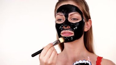 Genç bir kadın yüzüne karbonhidrat temizleme maskesi takıyor, yüzüne, beyaza. Genç kız yağlı cildiyle ilgileniyor, gözenekleri temizliyor. Güzellik tedavisi. Cilt bakımı.