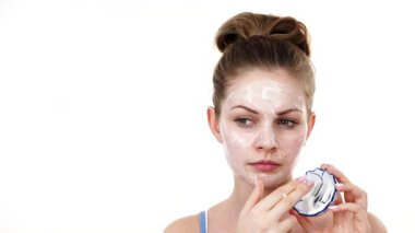 Maske takan genç bir kadın yüzüne nemlendirici krem sürüyor. Cilt nemlendiricisine dikkat eden bir kız. Cilt bakımı.