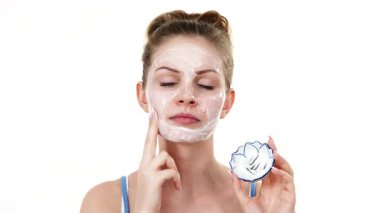 Maske takan genç bir kadın yüzüne nemlendirici krem sürüyor. Cilt nemlendiricisine dikkat eden bir kız. Cilt bakımı.