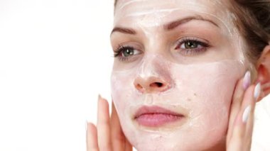 Maske takan genç bir kadın yüzüne nemlendirici krem sürüyor. Cilt nemlendiricisine dikkat eden bir kız. Cilt bakımı.