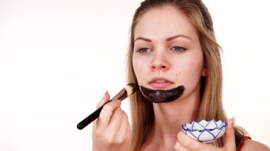 Genç bir kadın yüzüne karbonhidrat temizleme maskesi takıyor, yüzüne, beyaza. Genç kız yağlı cildiyle ilgileniyor, gözenekleri temizliyor. Güzellik tedavisi. Cilt bakımı.