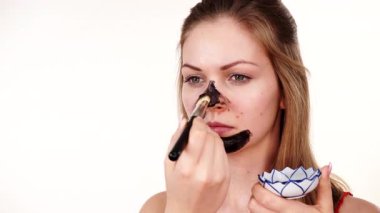 Genç bir kadın yüzüne karbonhidrat temizleme maskesi takıyor, yüzüne, beyaza. Genç kız yağlı cildiyle ilgileniyor, gözenekleri temizliyor. Güzellik tedavisi. Cilt bakımı.