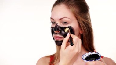 Genç bir kadın yüzüne karbonhidrat temizleme maskesi takıyor, yüzüne, beyaza. Genç kız yağlı cildiyle ilgileniyor, gözenekleri temizliyor. Güzellik tedavisi. Cilt bakımı.