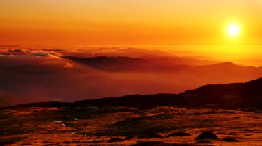 Bulutların üstündeki yüksek dağlarda yanan günbatımı. Portekiz 'de Serra da Estrela.