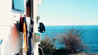 Sahilde kamp yapmak. Giysileri kurumaya bırakılmış bir karavan. Karavanla tatiller.