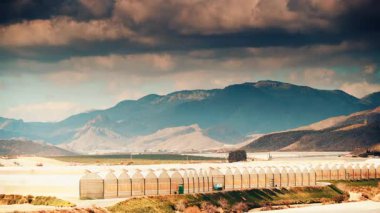 İspanya kıyılarında büyük ticari cam seralar ile hareket eden bulutların zaman akışı. Endüstriyel tarım. Murcia bölgesi, İspanya.