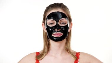 Yüzünde karbonhidrat maskesi olan genç bir kadın elinde kivi meyve yarımları, gözleri kaplayan beyaz bir kadın. Güzellik tedavisi. Cilt bakımı.