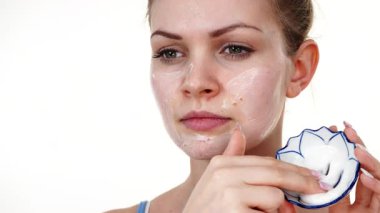 Maske takan genç bir kadın yüzüne nemlendirici krem sürüyor. Cilt nemlendiricisine dikkat eden bir kız. Cilt bakımı.