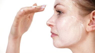 Maske takan genç bir kadın yüzüne nemlendirici krem sürüyor. Cilt nemlendiricisine dikkat eden bir kız. Cilt bakımı.